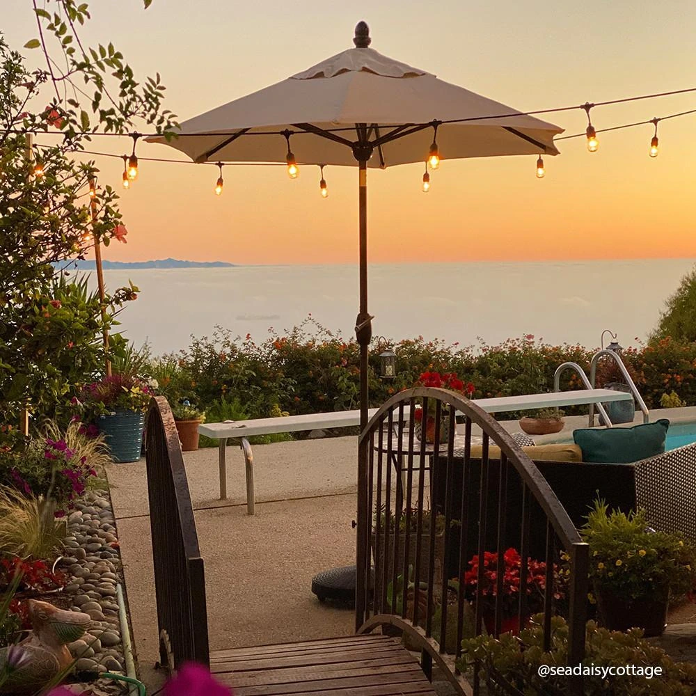 An outdoor patio with an umbrella at sunset overlooking the water